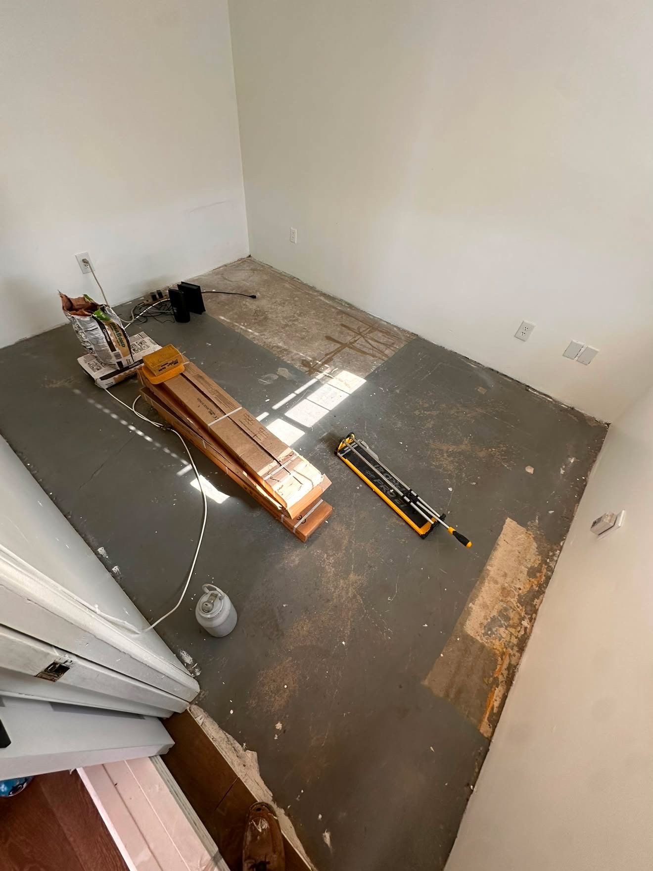 Empty room with bare subfloor and construction materials before flooring installation